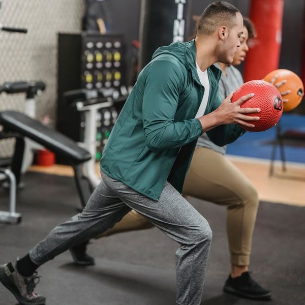 Person doing dynamic lunges in a dark minimalist gym