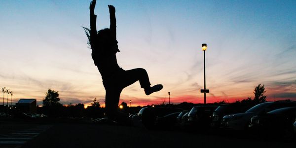 Silhouetted figure jumping against a bright teal background light